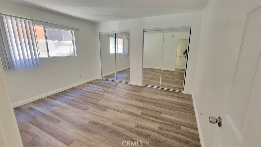 14817 Sylvan Street, Unit 3 Van Nuys, CA 91411 - Photo 7 of 12 a view of an empty room with wooden floor and a window