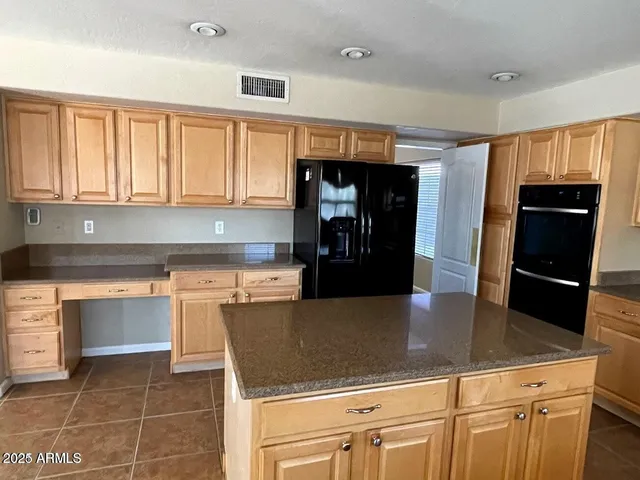 a kitchen with granite countertop a refrigerator a stove and white cabinets