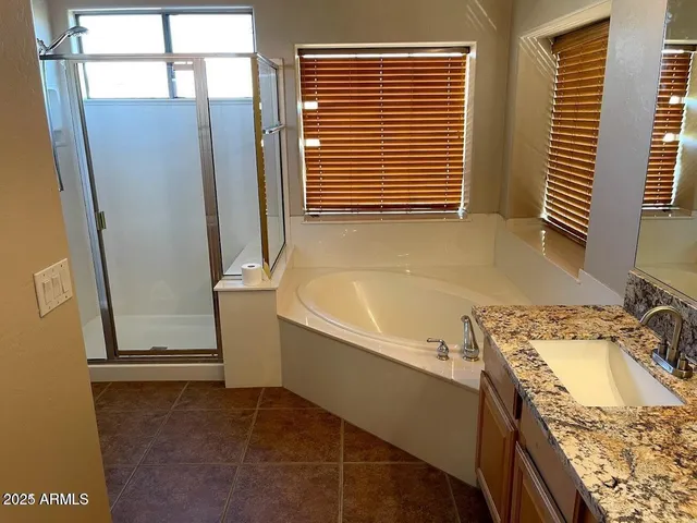a bathroom with a granite countertop sink and a tub