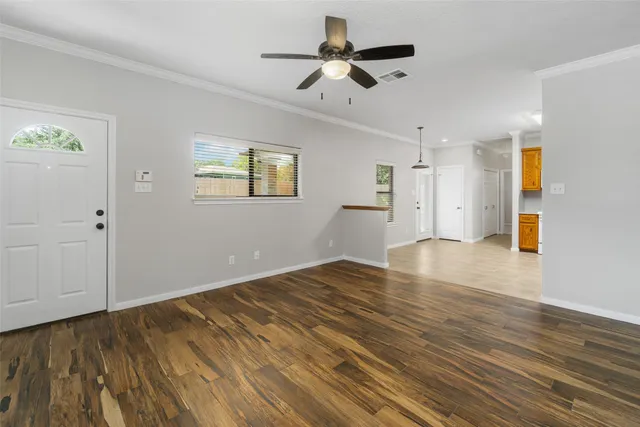 a view of empty room with wooden floor and fan