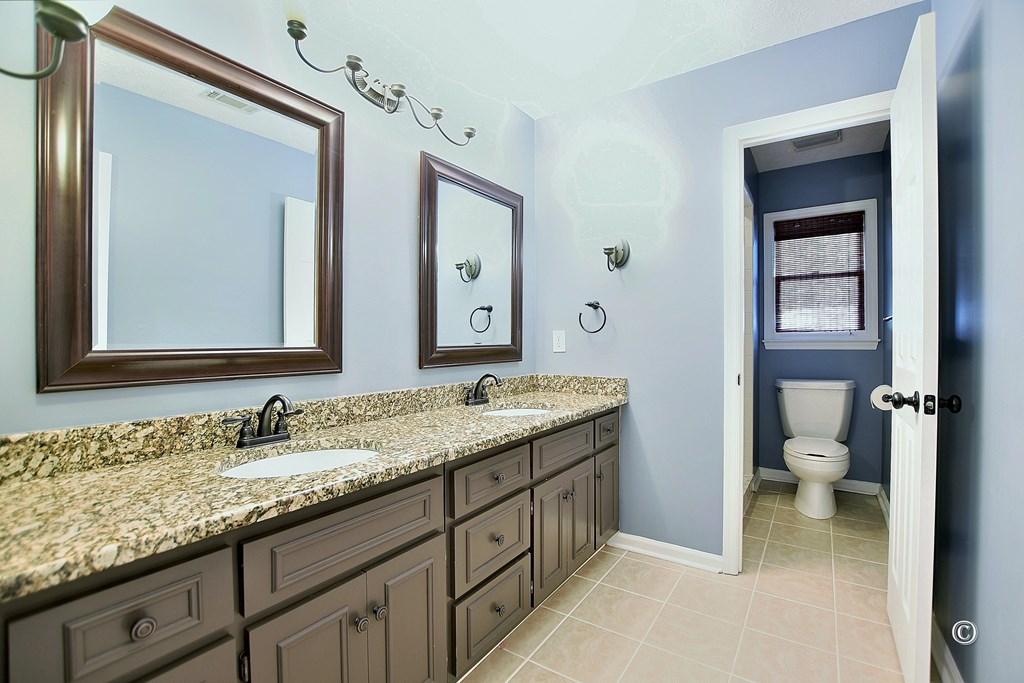 8935 K Moore Road Columbus, GA 31904 - Photo 13 of 36 a bathroom with a granite countertop sink a toilet and a mirror