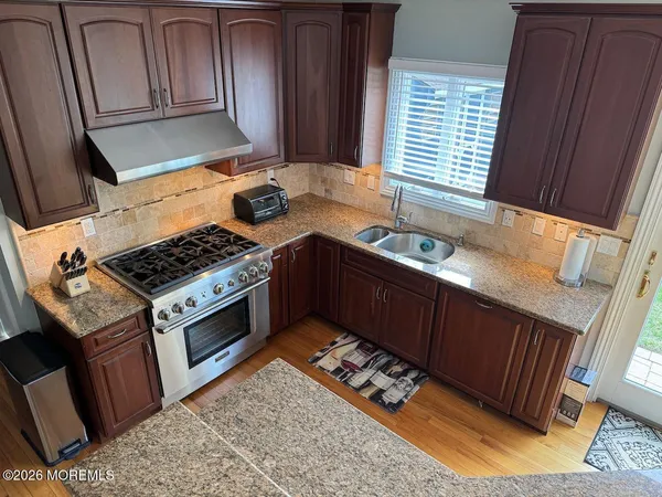 a kitchen with granite countertop a stove a sink dishwasher and cabinets