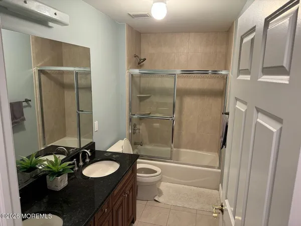 a bathroom with a granite countertop sink toilet and shower