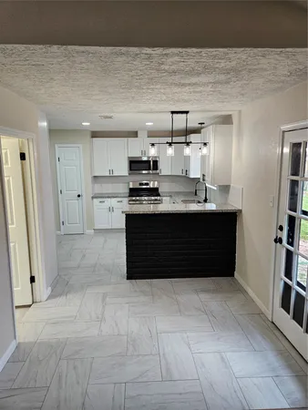 a living room with stainless steel appliances kitchen island granite countertop a refrigerator and a sink
