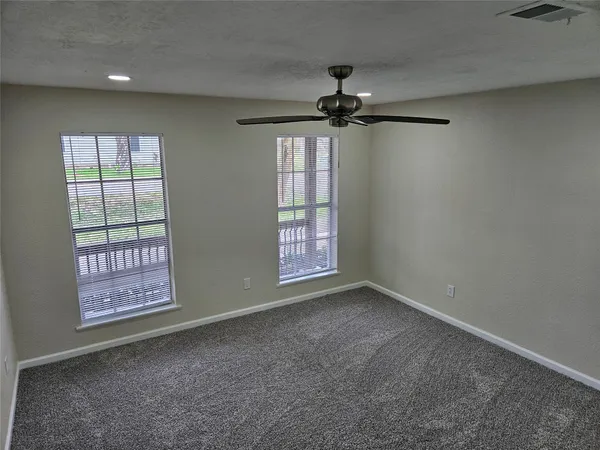 an empty room with windows and fan