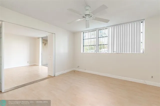 an empty room with chandelier fan and windows