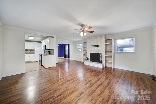 a view of a room with wooden floor and a kitchen