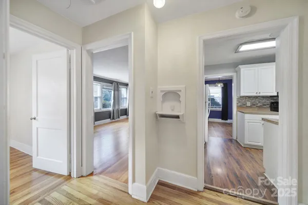 a view of a hallway with wooden floor kitchen and living room