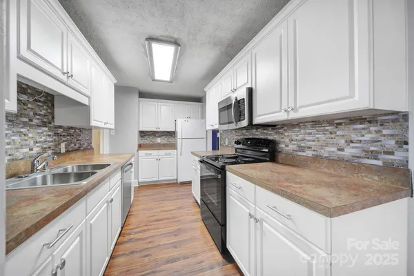 a kitchen with granite countertop a sink a counter top space stainless steel appliances and cabinets