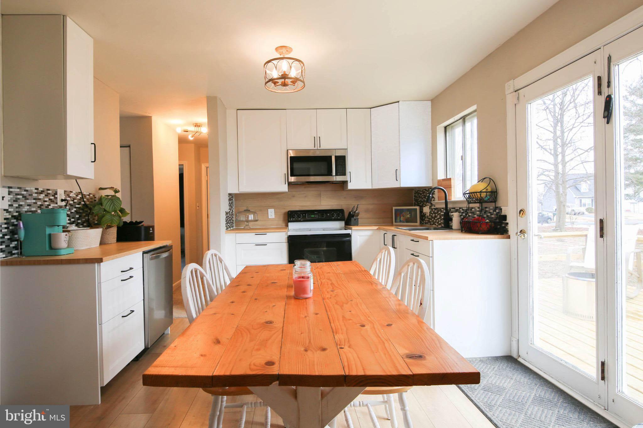 105 West Village Road Elkton, MD 21921 - Photo 8 of 32 a kitchen with stainless steel appliances kitchen island granite countertop a refrigerator a stove a microwave oven with a dining table and chairs
