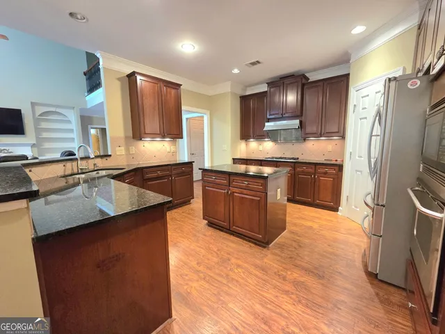 a large kitchen with stainless steel appliances granite countertop a sink stove and refrigerator