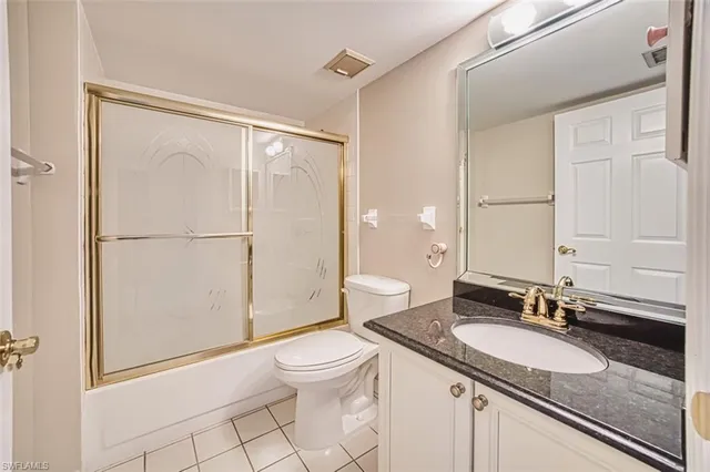 a bathroom with a granite countertop sink mirror vanity and toilet