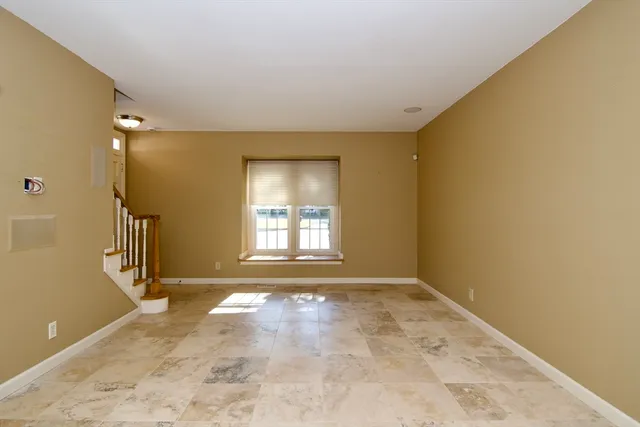 a view of an empty room with wooden floor and a bathroom
