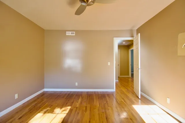 a view of a room with wooden floor and a ceiling fan
