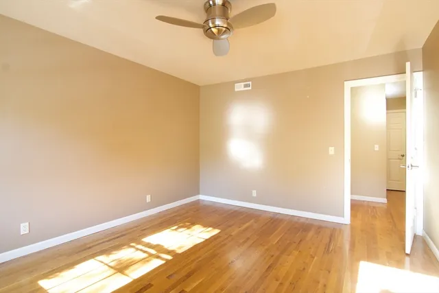 a view of an empty room with wooden floor and a bathroom