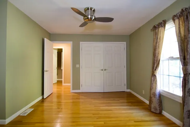 a view of a room with wooden floor and a ceiling fan