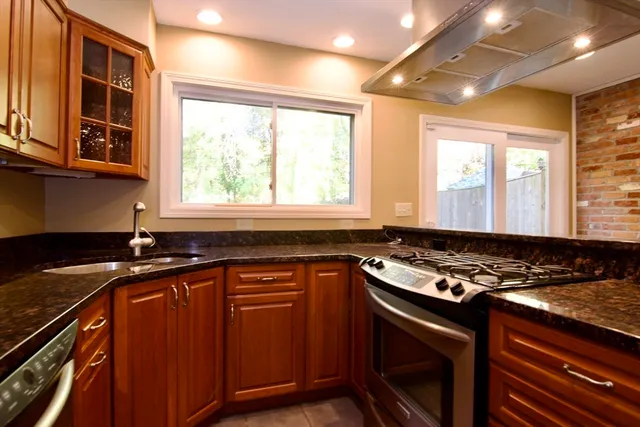 a kitchen with granite countertop a sink appliances cabinets and a window