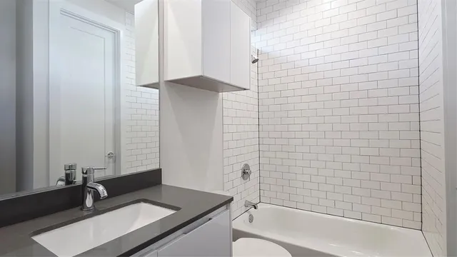 a bathroom with a granite countertop bathtub sink vanity and toilet