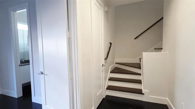 a view of a hallway with staircase and white walls