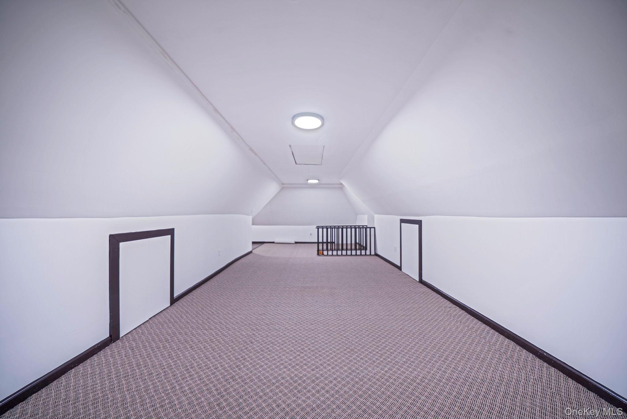 18240 Avon Road Queens, NY 11432 - Photo 24 of 30 Expansive attic space featuring sloped ceilings, recessed lighting, patterned carpeting, and multiple integrated storage access points
