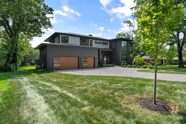 a front view of a house with a yard and trees