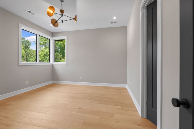 a view of an empty room with wooden floor and a bathroom