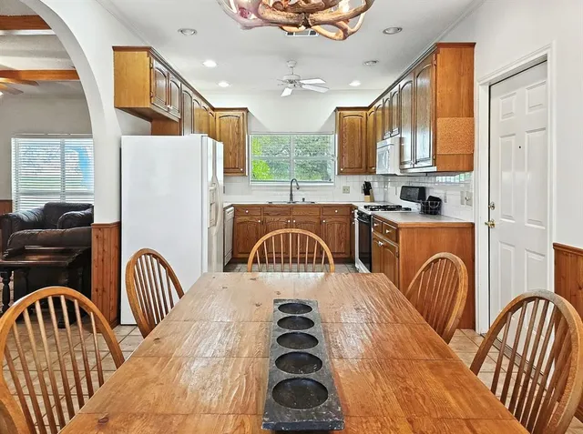 a kitchen with stainless steel appliances granite countertop a kitchen island a stove a sink a dining table and chairs