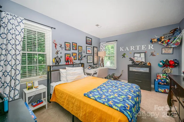 a bedroom with a bed a dresser and a floor to ceiling window