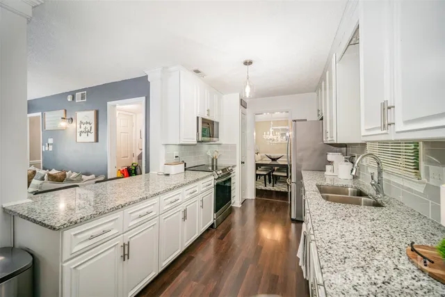 a large kitchen with granite countertop a large counter top space a stove a sink and cabinets