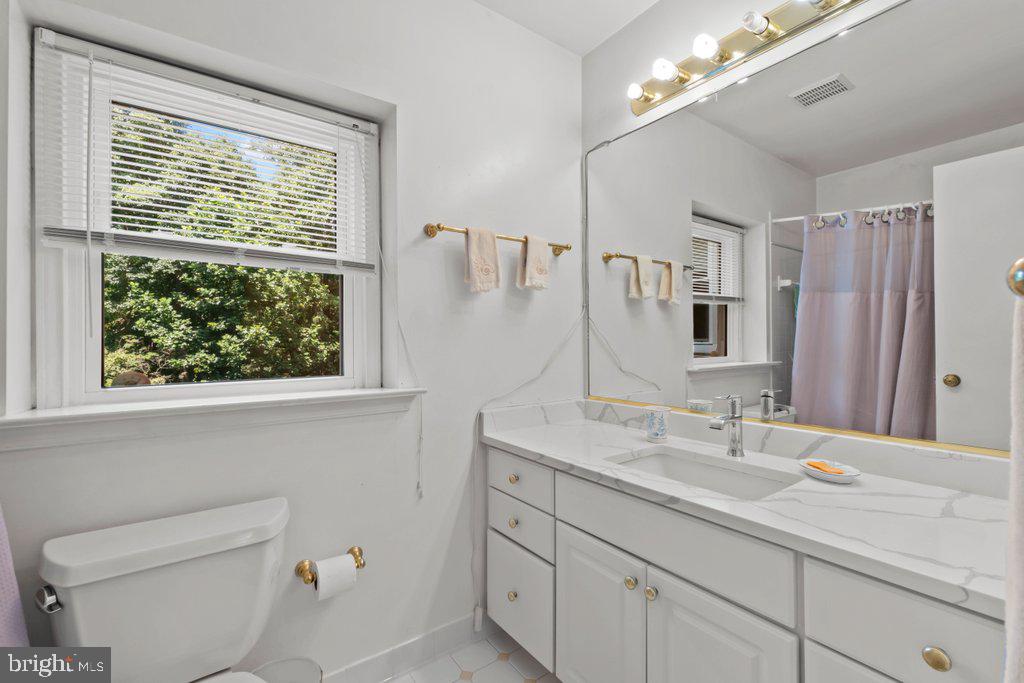 9704 Hall Road Potomac, MD 20854 - Photo 27 of 41 a bathroom with a granite countertop sink a toilet a large mirror and a window