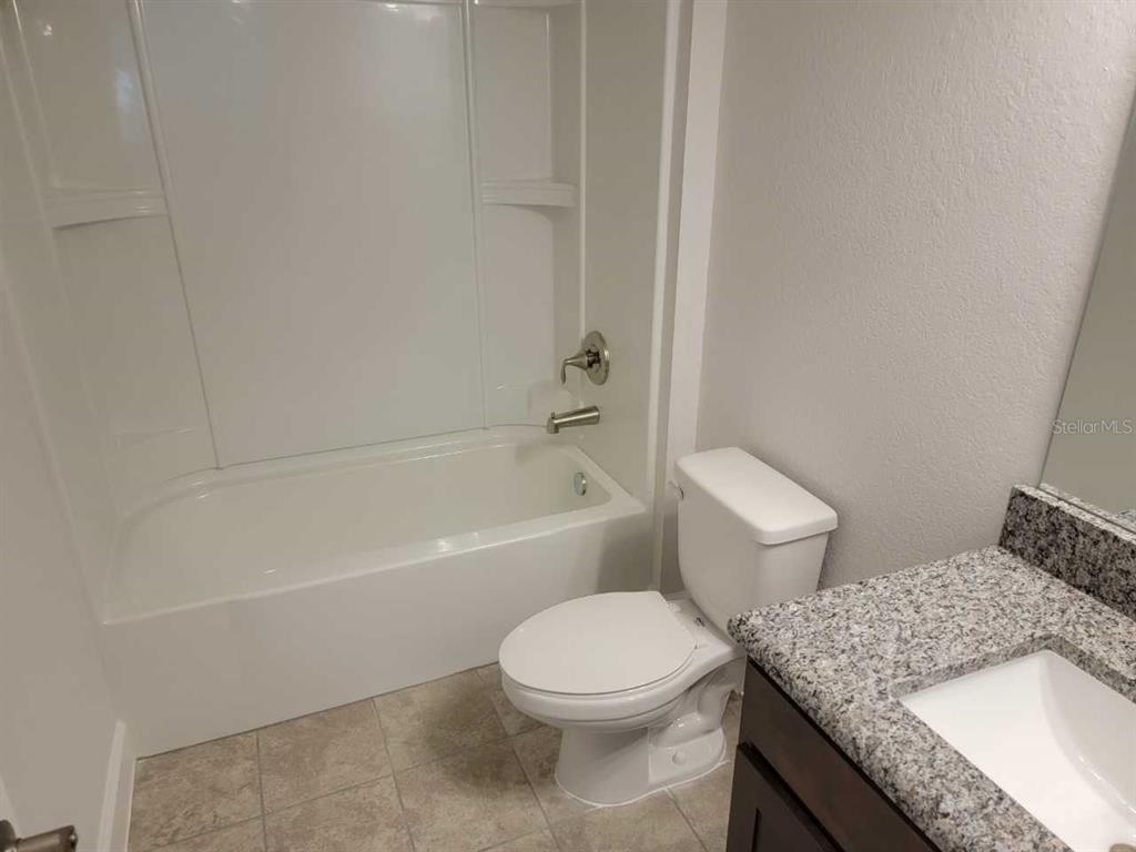 4380 Southwest 92nd Pl Road Ocala, FL 34476 - Photo 36 of 57 a bathroom with a granite countertop toilet a sink and bathtub
