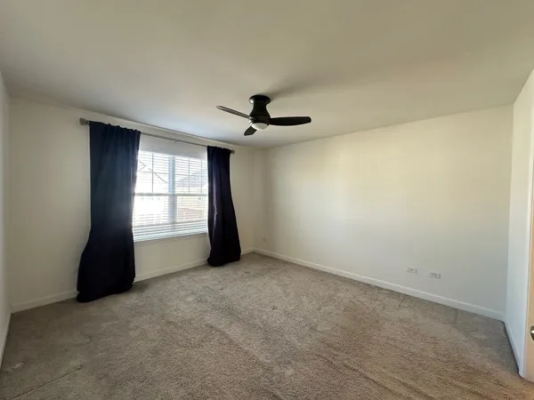an empty room with a window and a ceiling fan