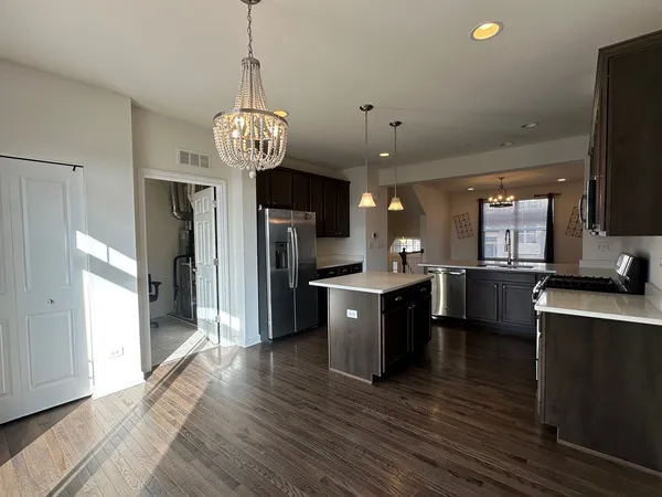 a kitchen with stainless steel appliances granite countertop a refrigerator a sink dishwasher a oven and a dining table with wooden floor