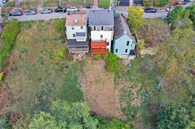 an aerial view of residential houses with outdoor space and trees