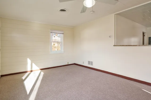 an empty room with windows and ceiling fan