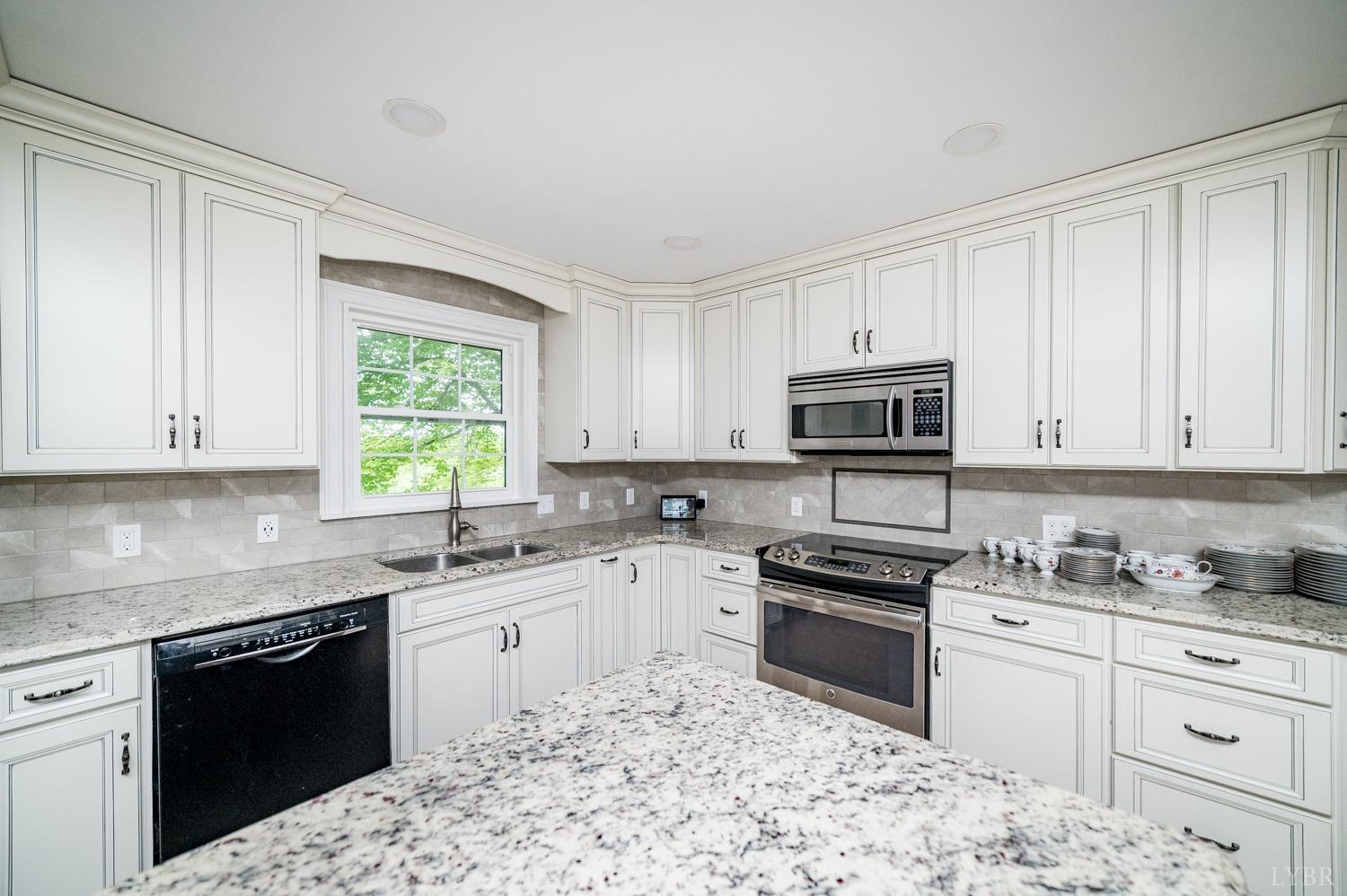 2901 Goode Station Road Goode, VA 24556 - Photo 52 of 57 a kitchen with granite countertop a sink stainless steel appliances and white cabinets