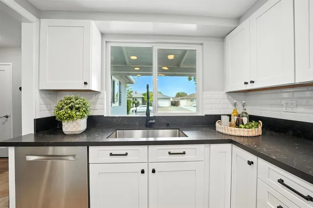 a kitchen with white cabinets and a potted plant