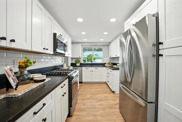 a kitchen with stainless steel appliances granite countertop a refrigerator a stove and a sink
