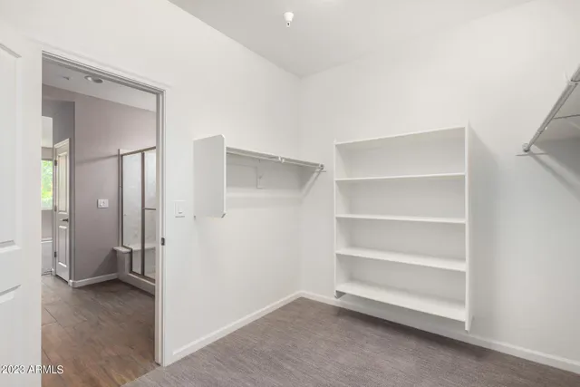 a view of an empty room with closet and a bathroom