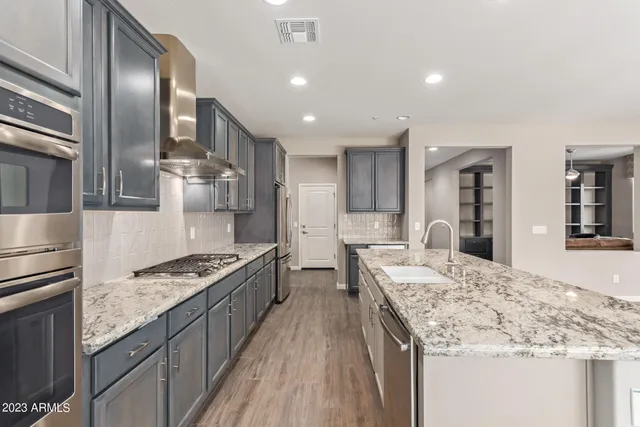 a large kitchen with stainless steel appliances granite countertop a lot of counter space and wooden floor
