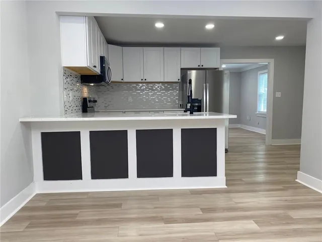 a kitchen with kitchen island granite countertop wooden cabinets and refrigerator