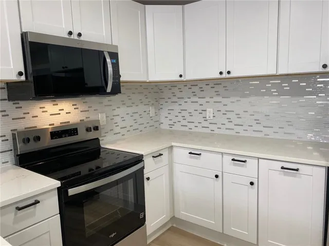 a kitchen with microwave cabinets and stove top oven