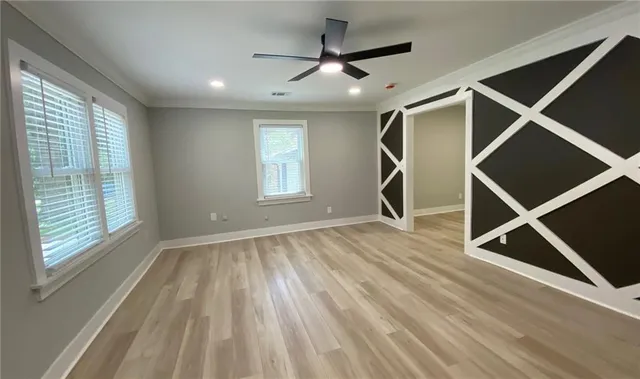 a view of an empty room with a window and wooden floor