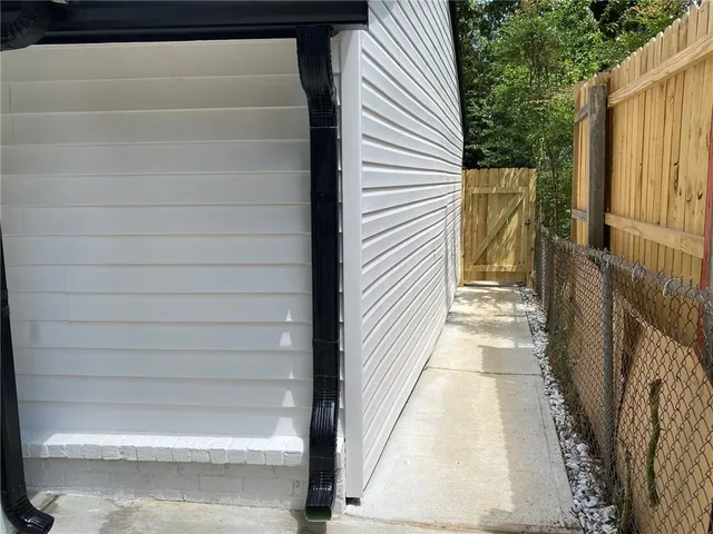 a backyard of a house with lots of plants and large tree