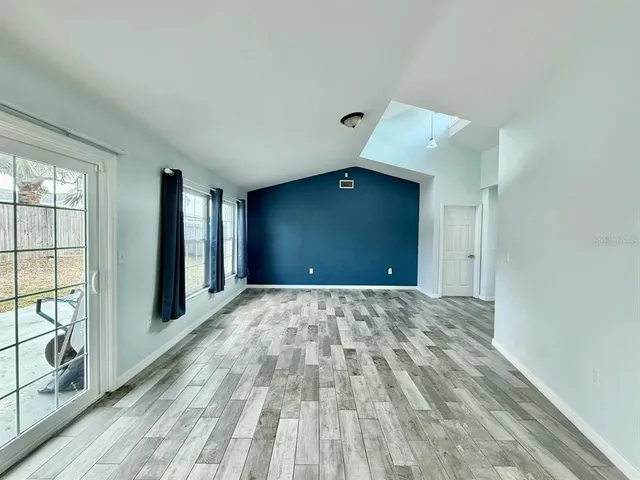 a view of an empty room with window and wooden floor