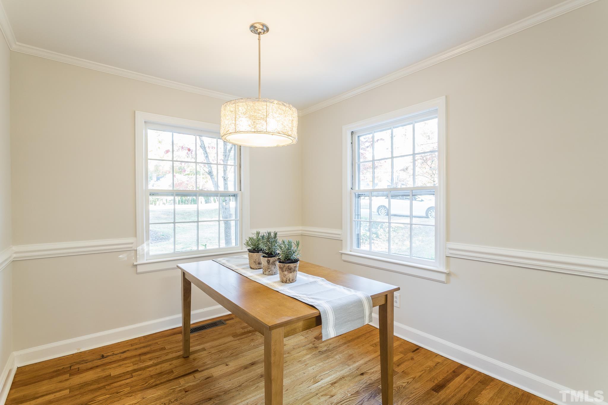 701 Dixie Trail Raleigh, NC 27607 - Photo 24 of 26 a dining room with wooden floor a chandelier a wooden table and chairs