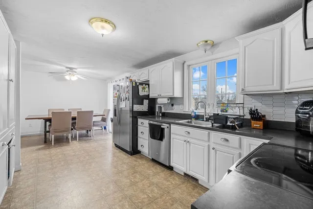 a kitchen with stainless steel appliances granite countertop a stove top oven a sink a dining table and chairs
