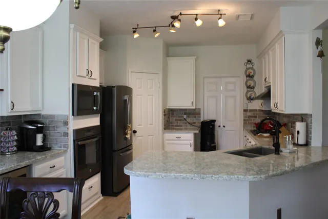 a kitchen with stainless steel appliances granite countertop a sink refrigerator and cabinets