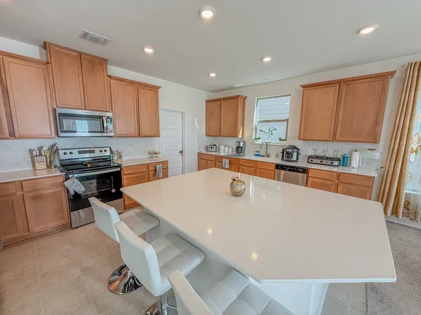 a large kitchen with kitchen island a stove a sink a refrigerator and cabinets