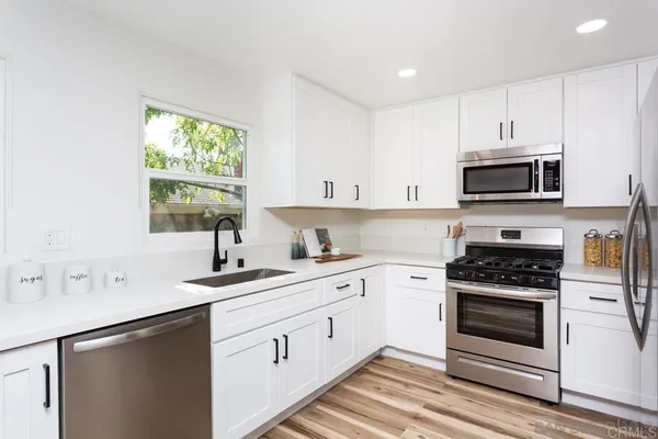 a kitchen with cabinets appliances a sink and a window